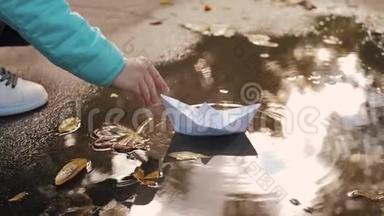 可爱的女孩在秋天公园的水坑里玩纸船。 童梦和旅行理念，生活方式..