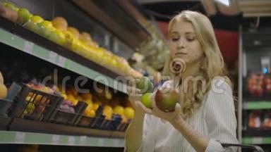 年轻的女人在杂货店里选择熟芒果。 纯素零废物女孩购买水果和有机织品