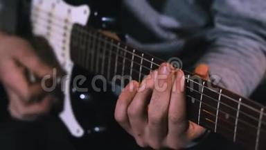 吉他手敲击电吉他的琴弦，以缓慢的动作合上男人的手指在吉他上弹奏音乐。