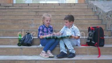 学校休息，小男孩和女孩交流和复习书坐在学校台阶旁边的背包在露天