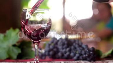 葡萄酒被倒入一个靠近一喷酒的<strong>玻璃杯中</strong>。 桌子上的葡萄酒和葡萄