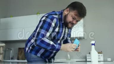 一个胖子在厨房里用粘胶布擦拭桌子。 一个人用清洁器清洁桌子的表面