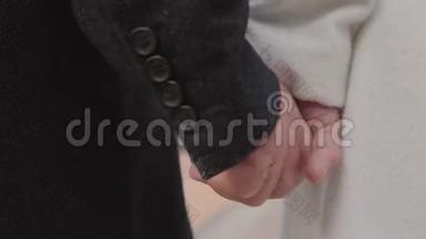成熟白种人双手合拢。 男的手穿黑色外套，女的手穿白色外套，互相抱着。