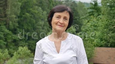 特写一位年长妇女的肖像，她留着一头乌黑的短发，<strong>满脸皱纹</strong>，微笑着看着山上的摄像机