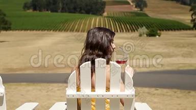 一位漂亮的酿酒厂里漂亮的年轻黑发女人坐着，随意地啜饮着一杯皮诺酒。