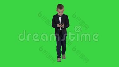 穿着服装走路和使用智能手机的小男孩在绿色屏幕上，Chroma键。