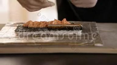 苏轼厨师汉兹的特写将熏鳗放在诺里叶和蟹肉上。 寿司制作工艺。 把寿司卷滚起来