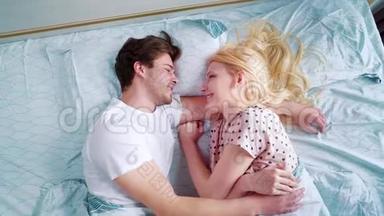 在早晨的床上放大年轻的微笑情侣