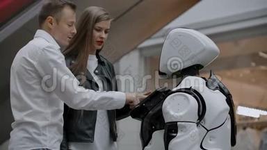 商场里的一男一女通过敲击屏幕和微笑与机器人顾问互动.. 安卓系统
