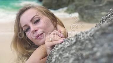 肖像美丽的女人微笑着，望着岩石海滩上的镜头。 面对夏天留长发的快乐女人