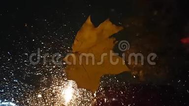 悲伤忧郁的框架：汽车挡风<strong>玻璃</strong>上<strong>掉落</strong>的枫叶和雨后的水滴。 秋天天气恶劣