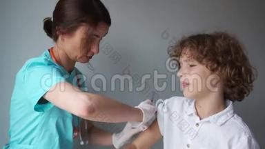 医生给一个卷发男生注射流感疫苗。 男孩和女人开心地笑着。 流感疫苗