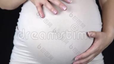 孕妇抚摸着她的胃，从手中露出一颗心。 穿着轻便T恤的女人