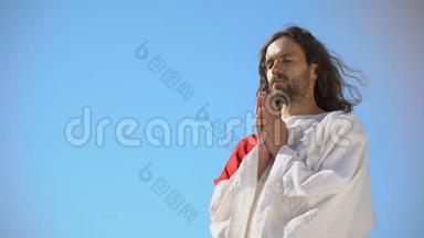 穿长袍的人在蓝天的背景下向上帝祈祷，请求灵魂的救赎