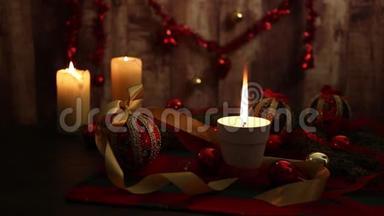 圣诞节的<strong>气</strong>氛：三支点燃的蜡烛，一支在前景上有大火焰的蜡烛，红色和<strong>金色</strong>的，脱钩的球，缎子<strong>金色</strong>的丝带