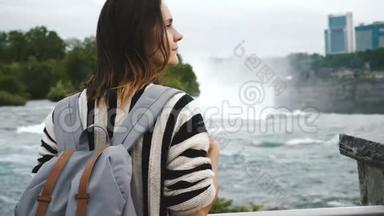 背面观看当地快乐的白人妇女与背包看右边，观看瀑布在尼亚加拉瀑布慢动作。