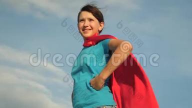 少女超级英雄穿着红色斗篷站在田野上，斗篷<strong>迎风飘扬</strong>。 慢动作。 女孩的梦想