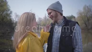 描绘了一对年轻可爱的夫妇在城外河边散步。 穿着黄色雨衣的金发美女