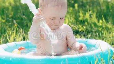 夏日绿草草坪上的充气池里，小男孩嬉水嬉戏