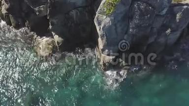 海浪飞溅到岩石悬崖无人机的视野。 透明的海浪在岩石悬崖上喷射，泡沫空中破碎