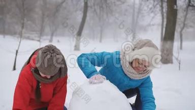 妈妈和两个女儿雕刻雪人。 一个幸福的家庭在冬天在外面堆雪人。