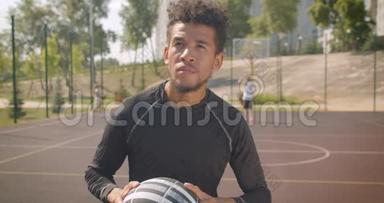 年轻英俊的非裔美国男篮球运动员在户外向篮筐投掷球的特写镜头