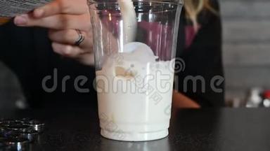 酒保把奶油倒入咖啡鸡尾酒。 咖啡师将牛奶倒入装有冰块的塑料杯中，准备冰镇咖啡。 A.