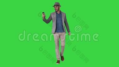 有魅力的男人穿着休闲服装，帽子，时髦的风格，记录Vlog或视频呼叫绿色屏幕，Chroma键。