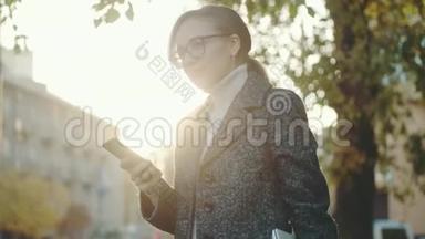 女人在户外使用智能手机。 戴眼镜和外套的女孩的肖像