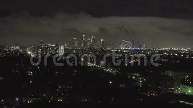 空中：<strong>夜晚</strong>在黑暗的好莱坞<strong>洛杉矶</strong>上空，市中心和城市灯光笼罩着云层