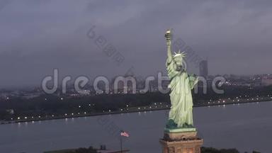 空中：自由女神像盘旋，在清晨的晨光中美丽地照亮了纽约市