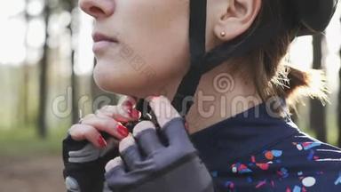 在铁人三项比赛前，有注意力的骑自行车的女人戴上头盔和夹子。 三项全能概念