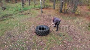 在秋天的森林里，强壮的人用沉重的锤<strong>击打</strong>卡车的轮胎