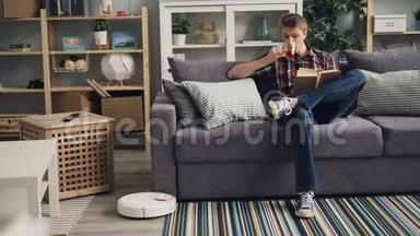 严肃的年轻人正在轻平地坐在沙发上喝<strong>茶</strong>和看书，而机器人吸尘器则是<strong>如</strong>此