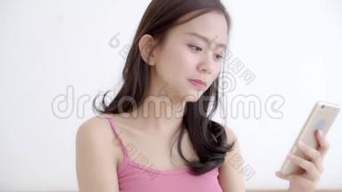 美丽的肖像年轻的亚洲女人微笑着坐着看着智能手机阅读社交网络与享受床