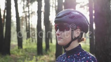 快乐三项运动员女孩戴着黑色头盔戴着自行车眼镜的肖像。 自行车的概念。 慢动作