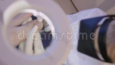 皮肤科医生与一个病人`拇指指甲。 通过美容放大镜的视角。 特写镜头。 五金修脚
