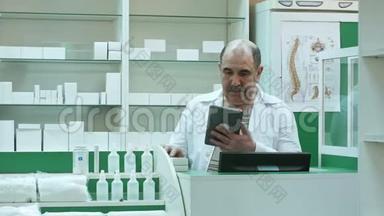 具有<strong>大胡子</strong>的高级药剂师在药房检查药品时使用平板电脑