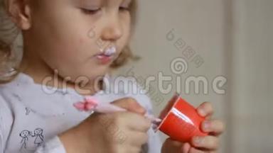 小女孩吃乳制品酸奶。 小孩<strong>用勺子</strong>吃奶酪。 肖像特写