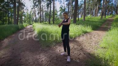 一位年轻女子手上拿着一只智能手表，想知道她在一个温暖的公园里跑了多少公里
