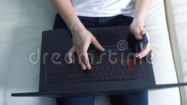 女孩用笔记本电脑数字平板电脑制作网上销售购物概念。 黑发女人躺在沙发上看店