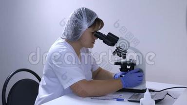 实验室技术员看着显微镜写下数据