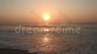 金色的阳光反射在海滩上。 太阳在傍晚照耀着——海浪在岸边拍打. 海滩上的金色阳光。 红太阳