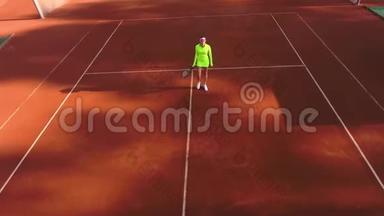 自信的漂亮女孩穿着运动服，拿着网球拍在网球场上打网球。 女网球