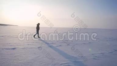 宽放大照片中的快乐男子在雪地上的阳光下向右行走。