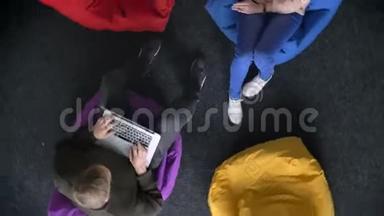 快速盘旋在<strong>上面</strong>的男人与<strong>笔记本</strong>电脑和女人在手机上坐在五颜六色的袋子。