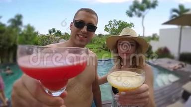 一对年轻可爱的夫妇在热带度假别墅的游<strong>泳池</strong>附近碰杯。