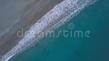 在蓝色海浪上方的沙滩无人机旋转中，高空俯视海浪破碎