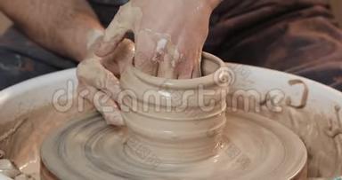 手中的陶工制作陶瓷制品的陶工`的车轮特写.. 手工制作，手工制作
