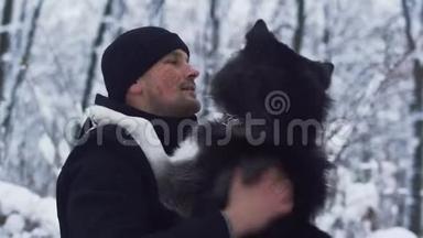 在冬天下雪的背景下，年轻人抓着一个美丽的西伯利亚哈士奇最好的朋友。 狗和主人